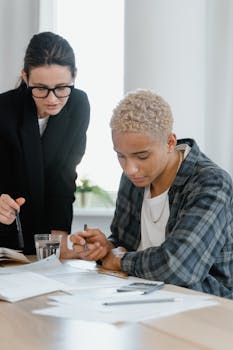 Two colleagues engaging in a collaborative work session, reviewing documents at a desk.